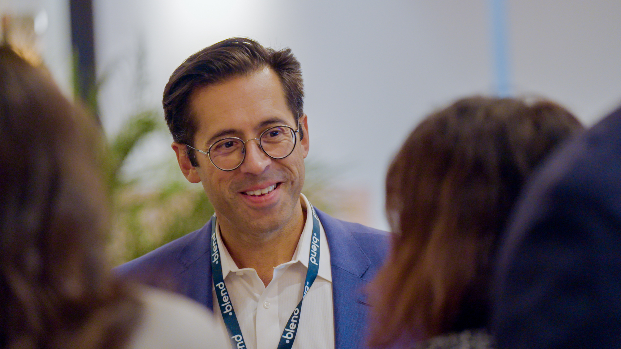 A C-suite professional networks at a Blend community networking event. He wears a Blend branded lanyard.