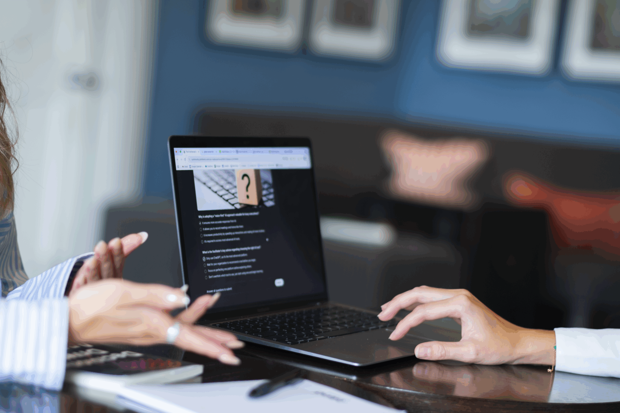Two people collaborating together; one works at a laptop and one gestures with her hands.
