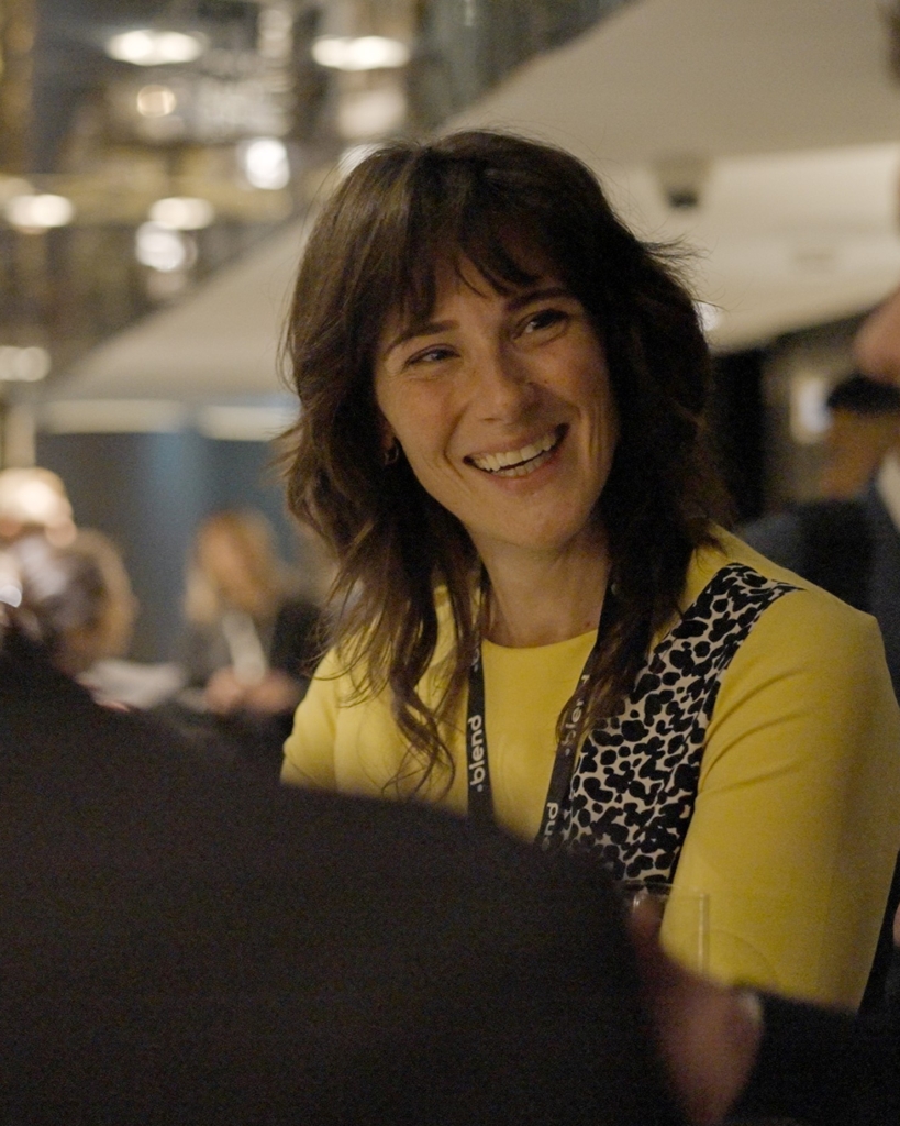 A smiling woman wearing a Blend lanyard at Blend community network event
